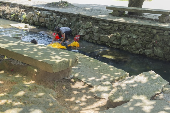 Woman washing laundry in a creek.